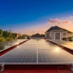 Residential solar panels installed on a red roof at sunset in a suburban neighborhood.