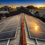 Sunset over a town with solar panels installed on a corrugated metal roof.